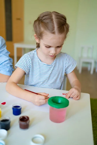 Klein meisje tekening met borstel en verf — Stockfoto