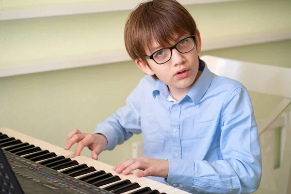 Niño con gafas aprende a tocar el sintetizador . — Foto de Stock