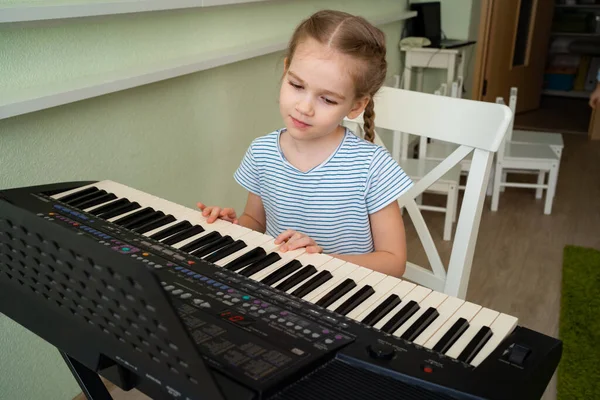 Ein kleines Mädchen lernt Synthesizer spielen. — Stockfoto