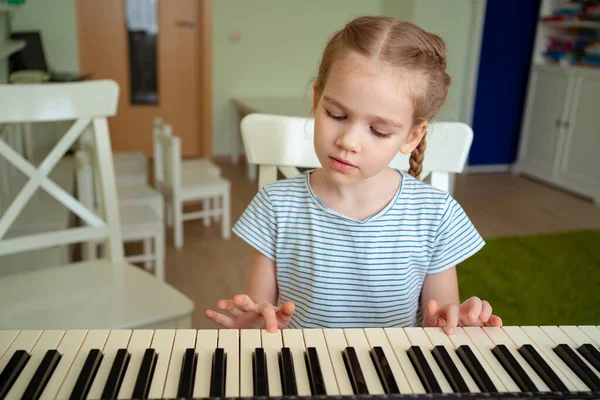 Une petite fille apprend à jouer du synthétiseur . — Photo