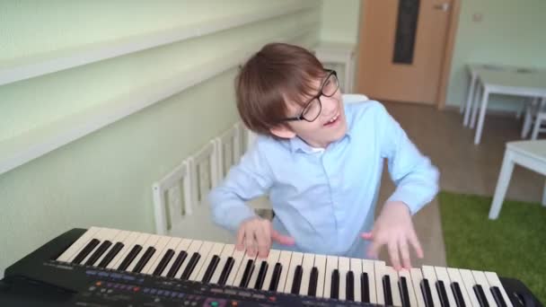Pojke med glasögon lär sig att spela synthesizer. — Stockvideo