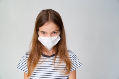 Beyaz arka planda tıbbi maskeli genç bir kız.