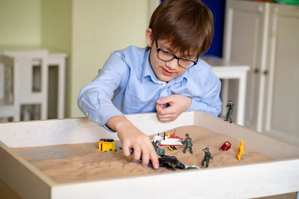 boy glasses is sand therapy on table with light