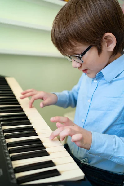 Niño con gafas aprende a tocar el sintetizador . — Foto de Stock