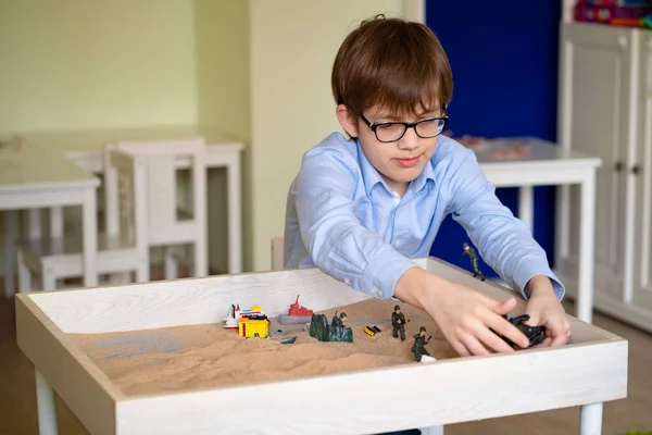 boy glasses is sand therapy on table with light