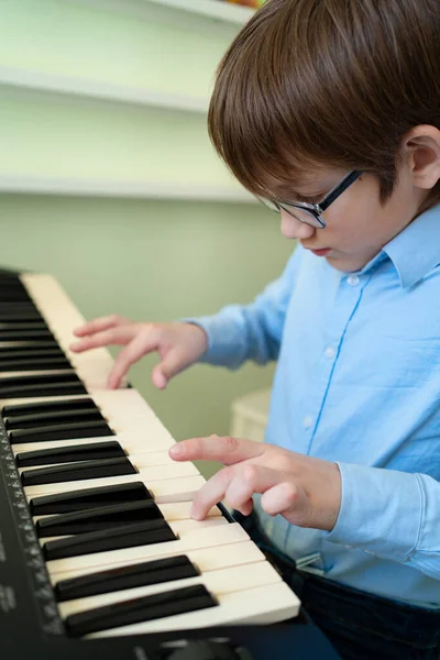 Niño con gafas aprende a tocar el sintetizador . — Foto de Stock