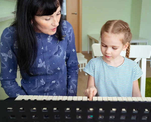 Profesor enseña a niña a jugar en el teclado . — Foto de Stock