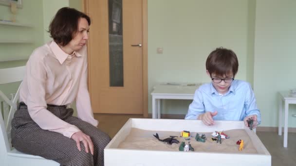 Jongen met leraar is zand therapie op tafel licht — Stockvideo