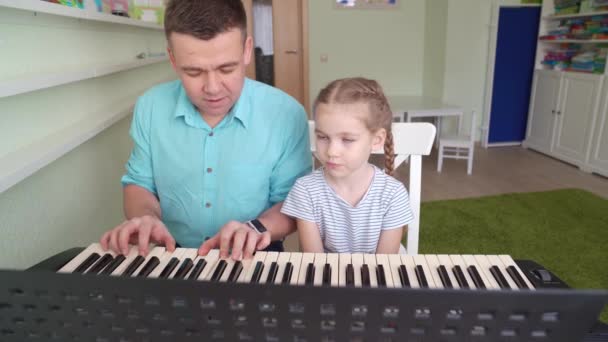 Papa enseigne petit fille jouer sur synthétiseur — Video