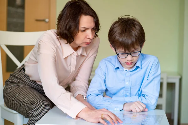 Mamá ayuda a su hijo a hacer la tarea. profesor ofertas chico . — Foto de Stock