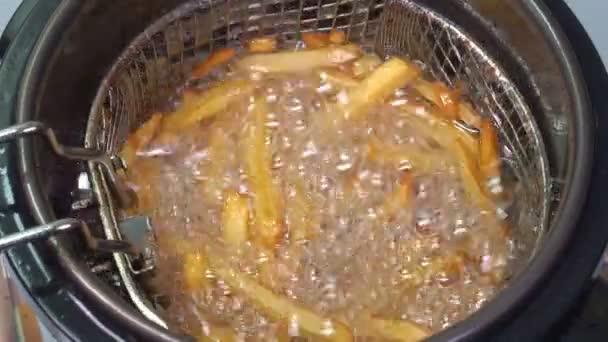 Batatas em óleo fervente em fritadeira cozinhe batatas fritas . — Vídeo de Stock