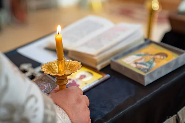 Präst hand hålla brinnande ljus i kyrkan. — Stockfoto