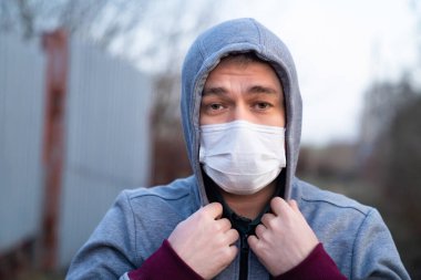 Sokakta maskeli, ceketli yetişkin bir adam.