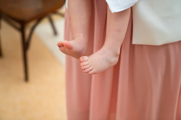 Ноги дитини в обіймах хрещеного батька в хрещенні . — стокове фото