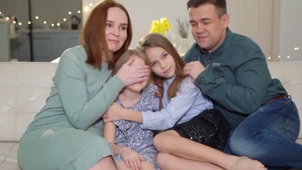 가족들은 소파에 앉아 아이의 눈을 감기 위해 TV 부모를 바라본다 — 비디오