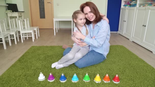 Mamá y niña abrazo jugar con coloridas campanas musicales — Vídeo de stock