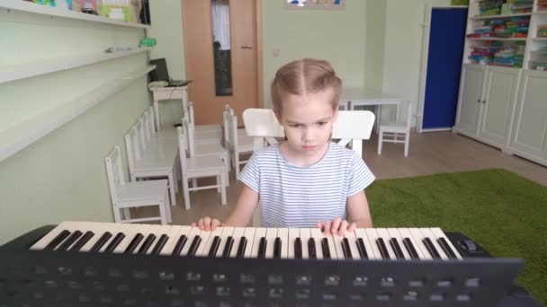 어린 소녀는 신시사이저를 연주하는 법을 배운다. — 비디오