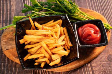Patates kızartması siyah tabak, yeşillik ve sos.