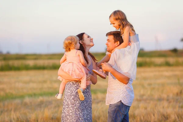 Família joga ao pôr do sol no campo de campo — Fotografia de Stock