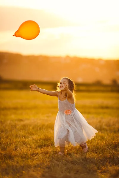 Маленькая девочка серый платье запустить воздушный шар на пшеничном поле — стоковое фото