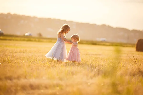 Kleine meisjes hand in hand staan op hellend veld — Stockfoto