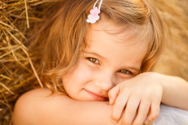 Küçük kız saman yığınının yanına otur. Yaklaş..