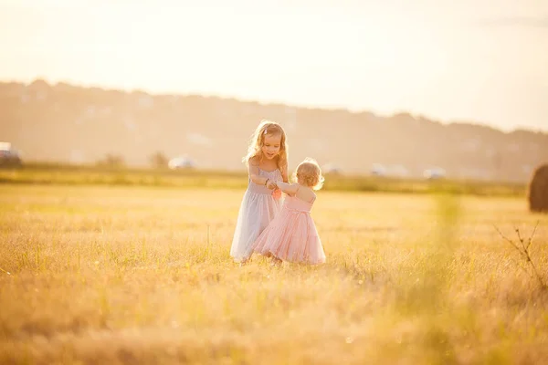 A lejtős búzamezőn a kislányok együtt forognak — Stock Fotó
