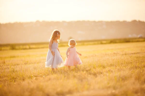 Niñas va en pendiente campo de trigo puesta del sol —  Fotos de Stock