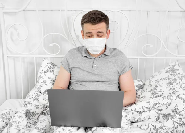 Maskeli bir adam yatak odasında, evden maske takıyor..