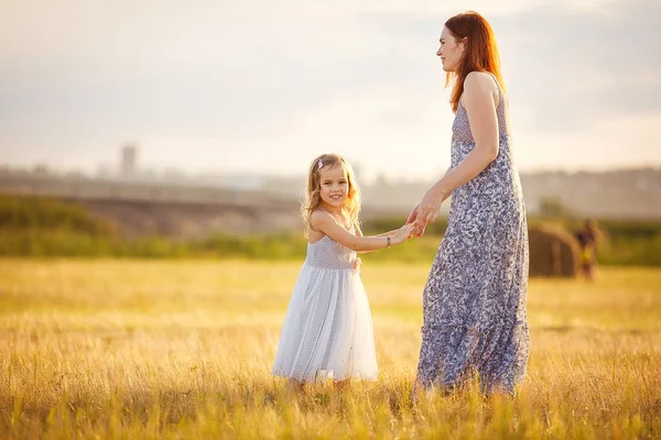 Moeder houden weinig dochter in grijs jurk in veld — Stockfoto