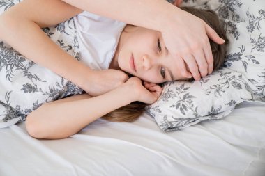 Küçük kız hasta, annesiyle yatakta yatıyor. Evde kal..