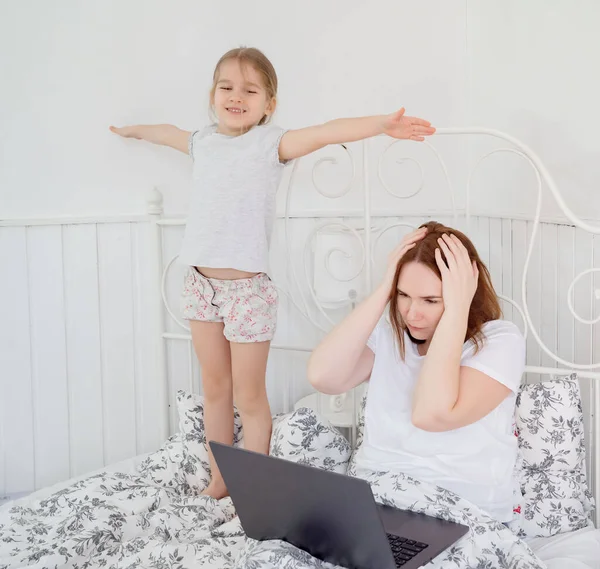 Liten flicka stör mamma att arbeta hemma. — Stockfoto