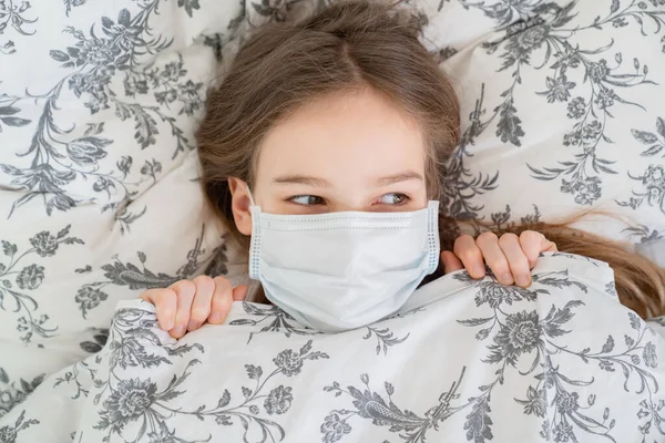 Adolescente chica acostada en la cama en un médico máscara . — Foto de Stock