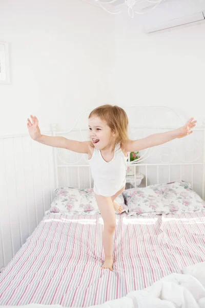 Niña saltando en la cama en el dormitorio de los padres . — Foto de Stock