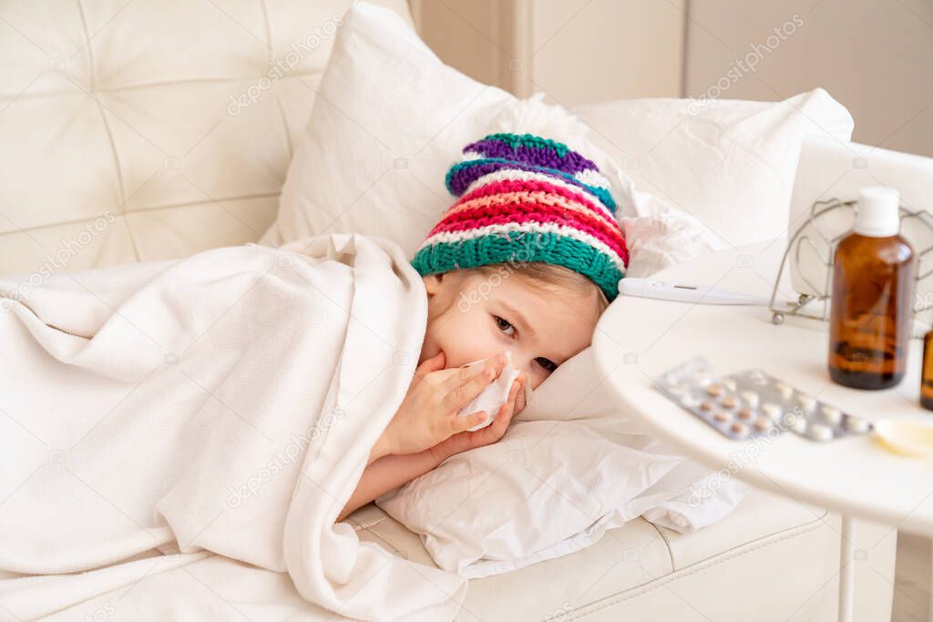 girl is sick, has runny nose, colorful hat