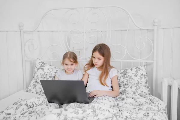 Niñas estudio en la computadora en línea en la cama en casa . — Foto de Stock
