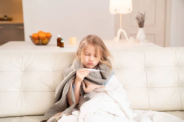 Niña pequeña en bufanda enferma, mide la temperatura . — Foto de Stock