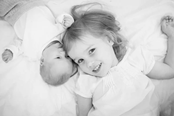 Grote zus liggend naast een pasgeboren baby. — Stockfoto