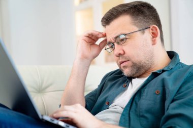 Gözlüklü serbest çalışan biri internette koltukta yatıyor.