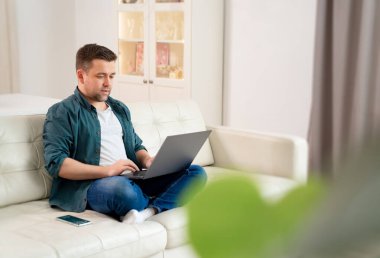 İnternette çalışan serbest çalışan biri kanepede oturuyor..