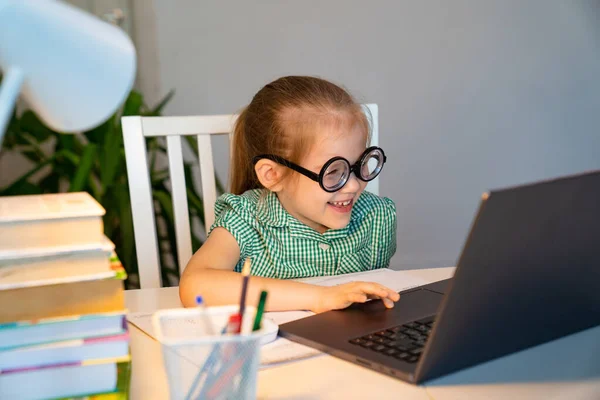 Divertida niña en gafas grandes aprendizaje en el ordenador portátil . — Foto de Stock