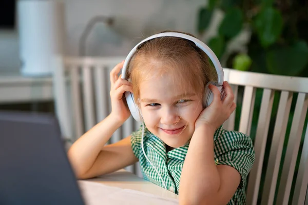 Kleines Mädchen mit Kopfhörer hört Unterricht auf Laptop — Stockfoto