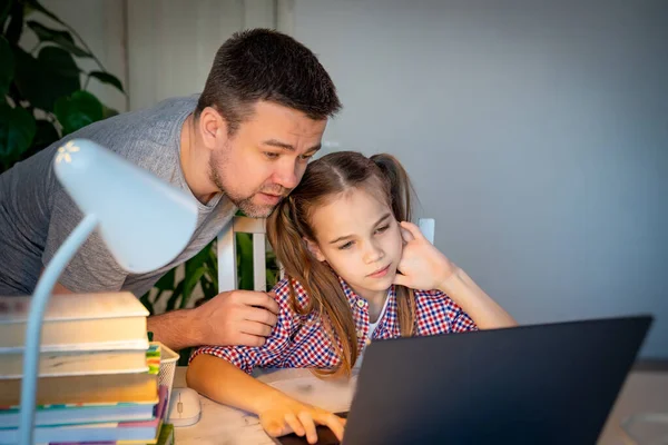 Babası, kızına bilgisayardaki internet derslerinde yardım ediyor.