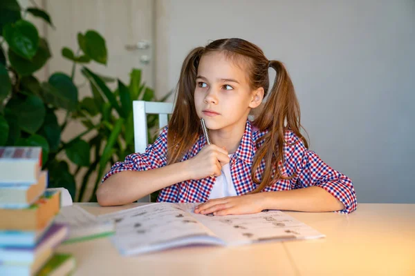 Nastolatka dziewczyna w kratę koszula robi pracę domową — Zdjęcie stockowe