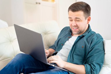 İnternette çalışan serbest çalışan bir adam kanepede yatıyor..