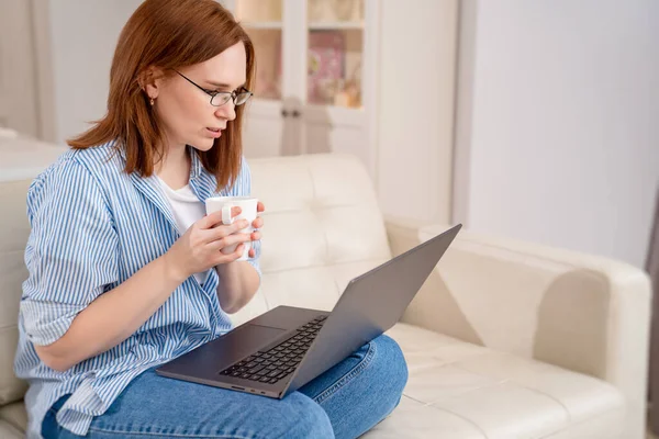 Freelancer kobieta pracuje przy komputerze, pije herbatę. — Zdjęcie stockowe