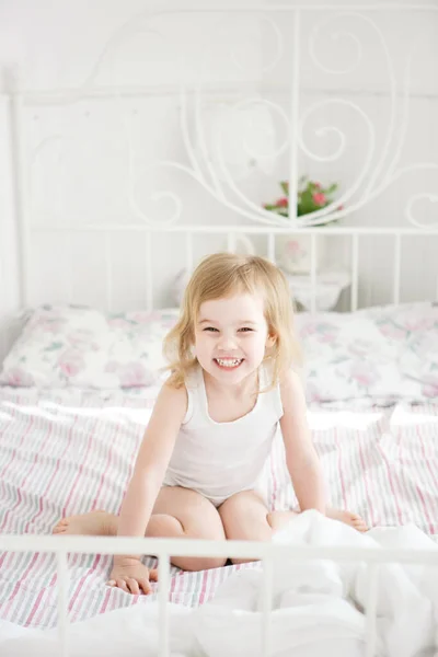 Chica risas sentado en la cama en padres dormitorio . — Foto de Stock