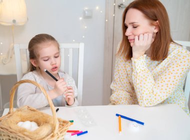 Anne ve çocuk marker stencil paskalya yumurtalarını süsler.