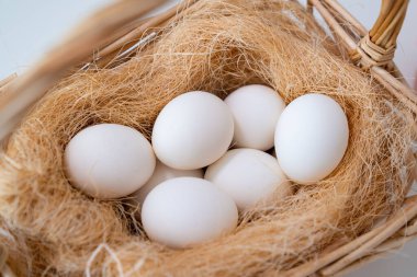 Sepetteki saman yuvasında beyaz yumurtalar. 