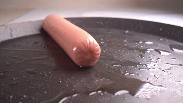 Uma salsicha cai em uma frigideira quente. câmara lenta — Vídeo de Stock